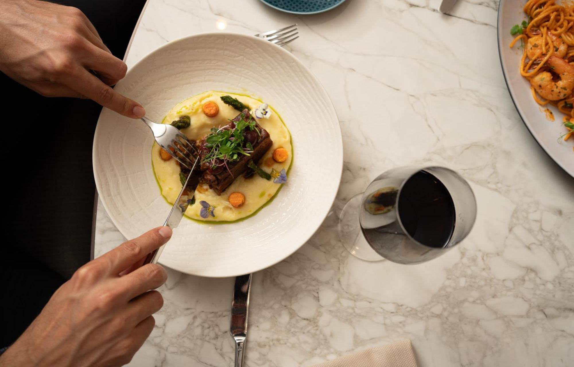 Address Istanbul Hotel Exterior foto A person using a fork to cut into a meal